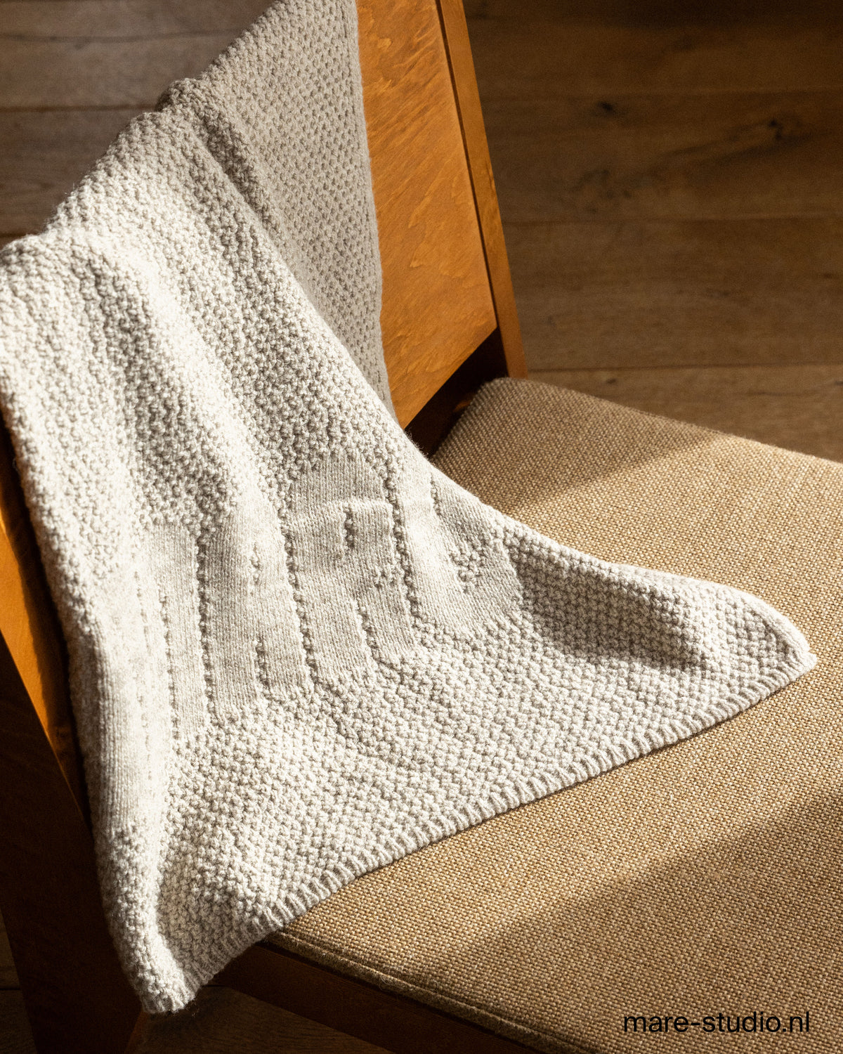 Knitted baby throw on wooden chair – 100% Dutch Merino wool, soft natural white by Mare Studio
